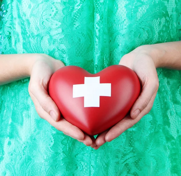 Coeur avec signe de croix dans les mains féminines — Photo