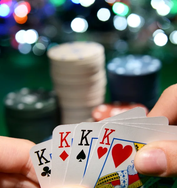 Patatine e carte per il poker in mano sul tavolo verde — Foto Stock