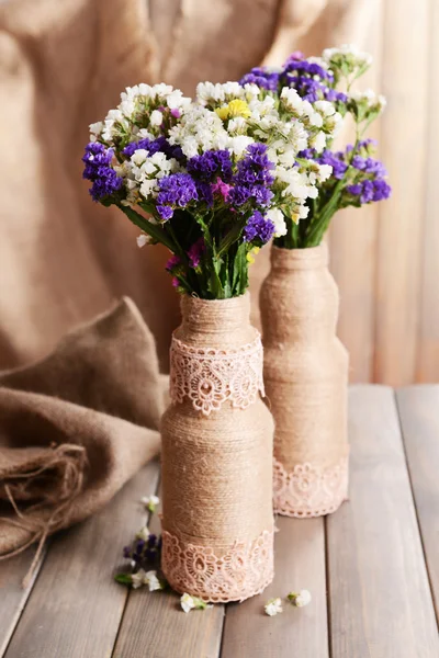 Vacker bukett av ljusa blommor i vas på bordet på brun bakgrund — Stockfoto
