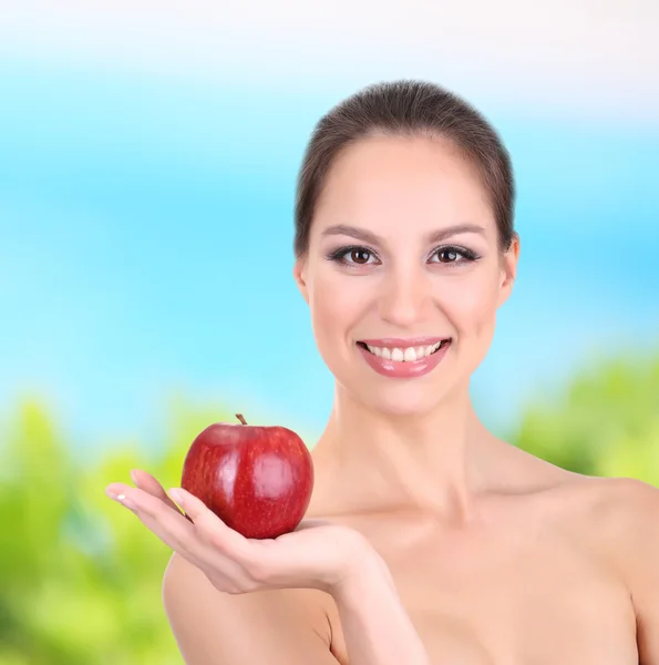 Mujer sonriente con manzana sobre fondo natural —  Fotos de Stock