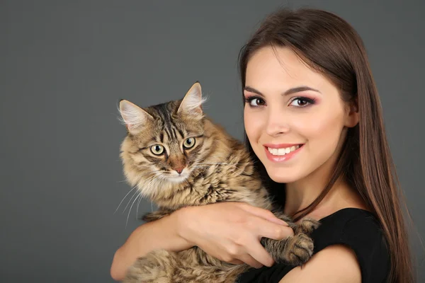 Hermosa mujer joven sosteniendo gato sobre fondo gris — Foto de Stock