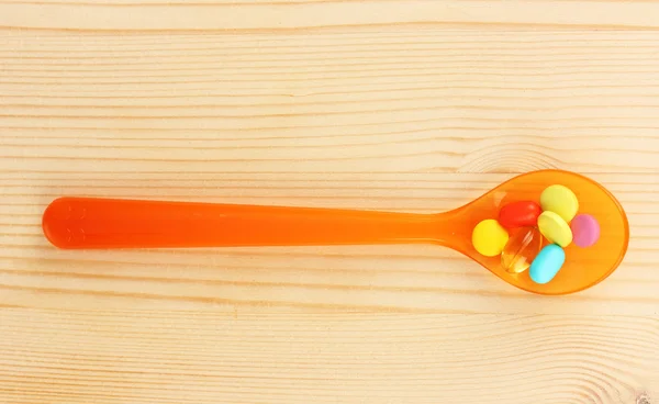 Plastic spoon with color pills — Stock Photo, Image