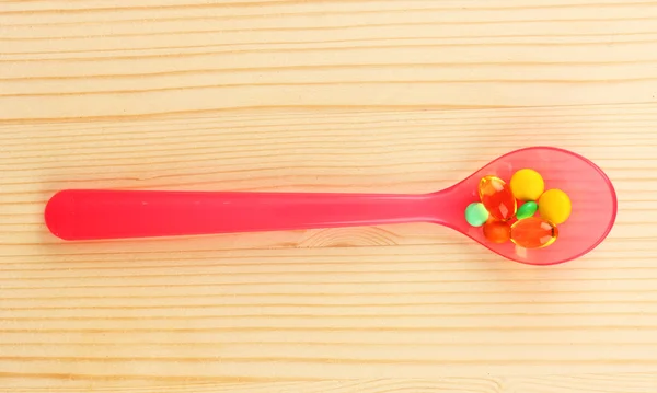 Plastic spoon with color pills — Stock Photo, Image