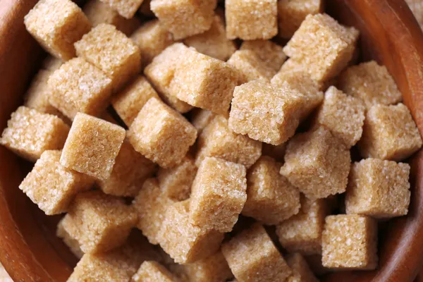 Cubos de açúcar mascavo na tigela em fundo de pano de saco — Fotografia de Stock