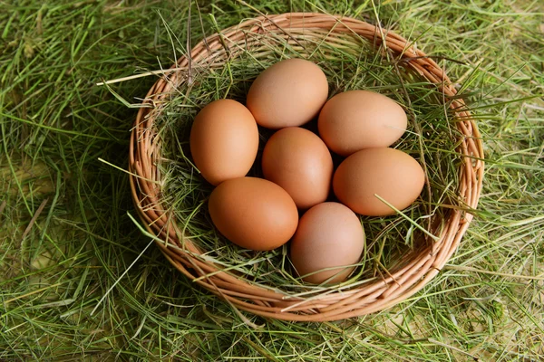 Huevos en canasta de mimbre en primer plano de la mesa — Foto de Stock