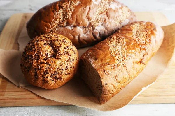 Fresh baked bread, on cutting board, on wooden background — Stock Photo, Image