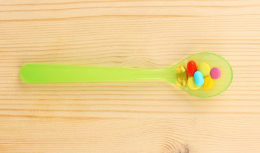 ahşap arka plan üzerinde renkli hapları ile plastik kaşık