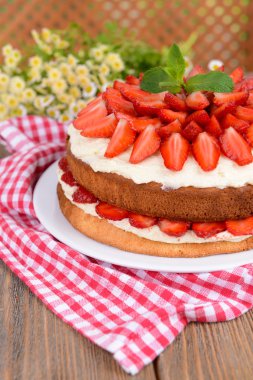 Kahverengi zemin üzerine masada çilek ile lezzetli bisküvi pasta