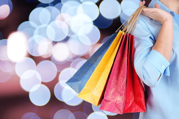 Mujer sosteniendo bolsas de regalo de colores sobre fondo brillante —  Fotos de Stock