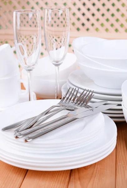 Set weißer Gerichte auf Tisch auf hellem Hintergrund — Stockfoto