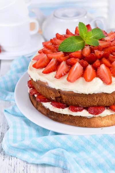 Delicious biscuit cake with strawberries on table on light background — Stock Photo, Image