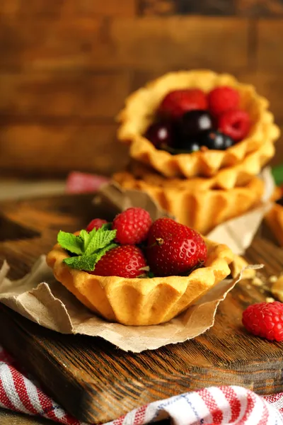 Tasty tartlets with berries on wooden table — Stock Photo, Image