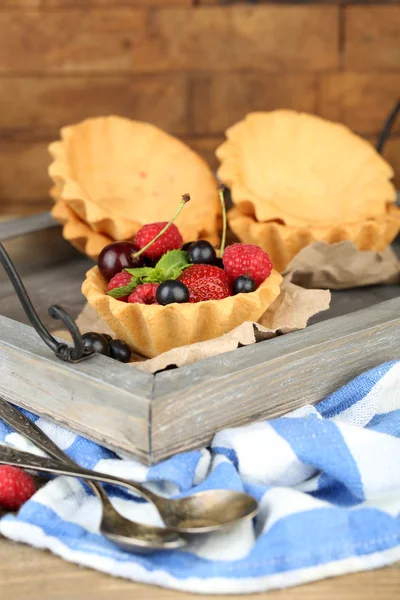 Tasty tartlets with berries on wooden tray — Stock Photo, Image