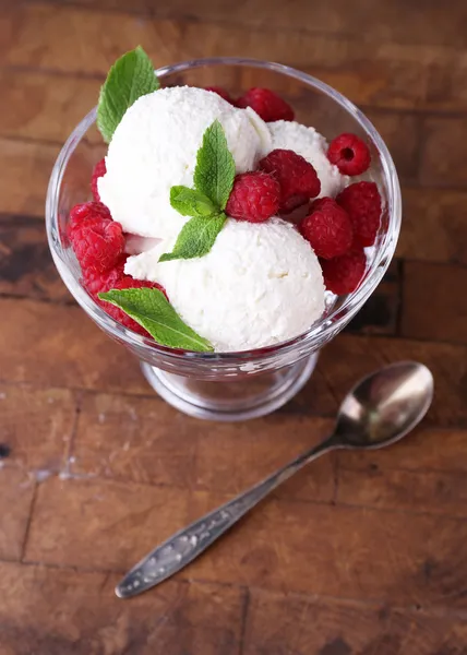 Creamy ice cream with raspberries on plate in glass bowl, on color wooden background — Stock Photo, Image