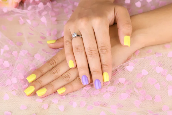 Female hand with stylish colorful nails, on color fabric background — Stock Photo, Image