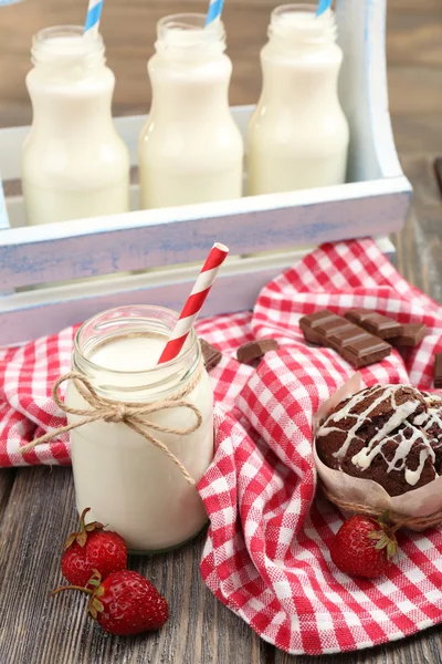 Melk in flessen met papier rietjes op tafel — Stockfoto