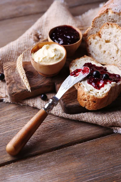 Fresh bread with homemade butter and blackcurrant jam on wooden background — Stock Photo, Image