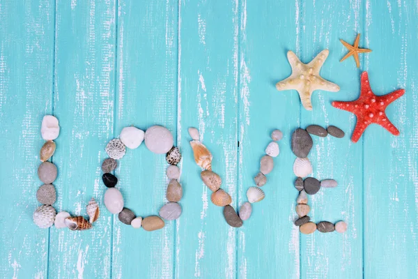 Word love made from sea shells and stones on wooden background — Stock Photo, Image