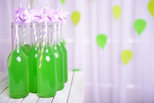 Бутылки напитка с соломой на столе на декоративном фоне — стоковое фото