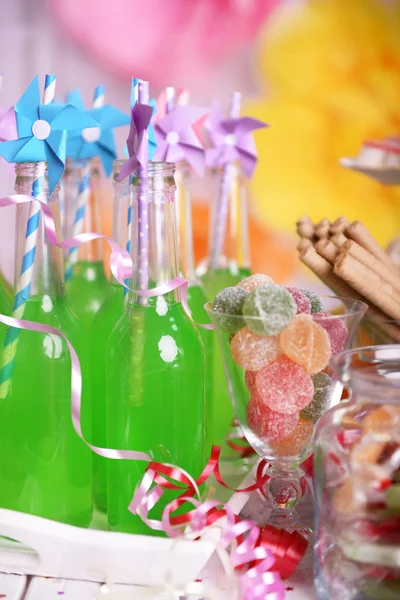 Bottles of drink with straw and sweets on decorative background — Stock Photo, Image