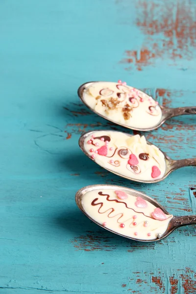 Lepels met lekkere chocolade voor derden op oude blauwe houten tafel — Stockfoto