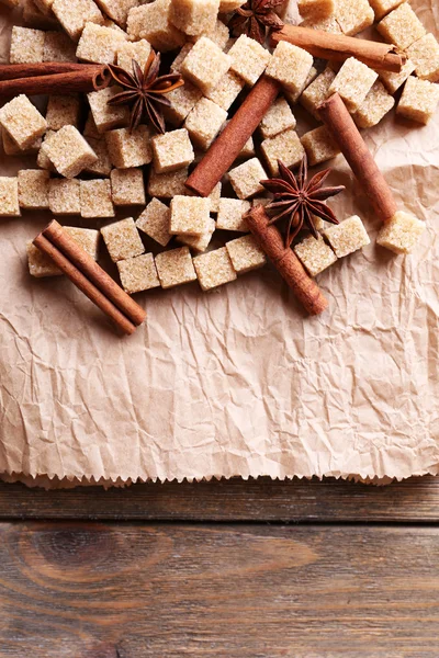 Bruine suiker kubussen en specerijen op papier achtergrond — Stockfoto