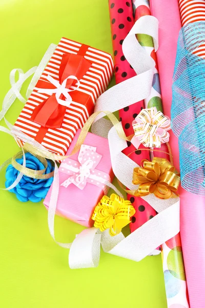 Rolls of Christmas wrapping paper with ribbons, bows on color background — Stock Photo, Image