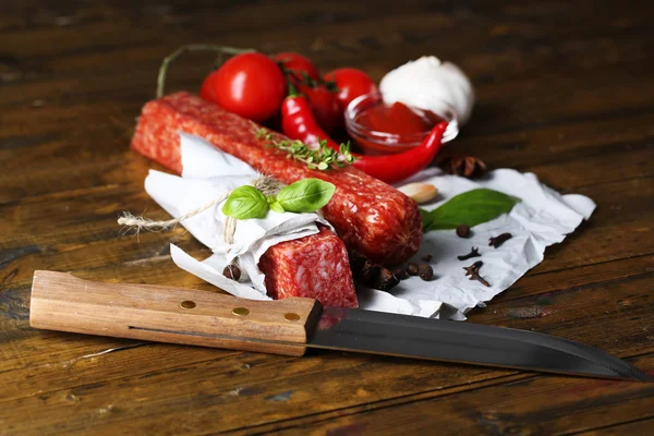 Leckere Salamiwurst und Gewürze auf Holzgrund — Stockfoto