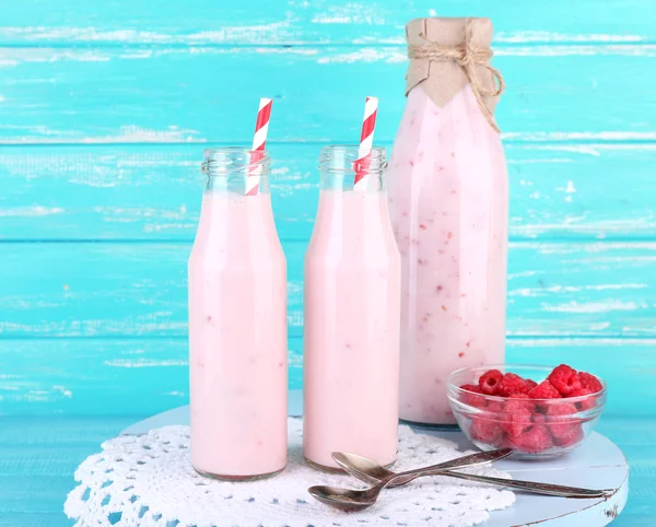 Bottles of raspberry smoothie drink on wooden background — Stock Photo, Image