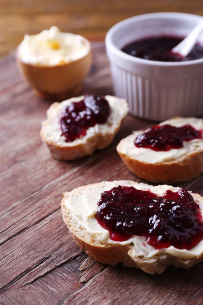 Vers brood met zelfgemaakte boter en kreken van zwarte jam op houten achtergrond — Stockfoto