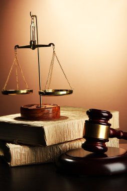 Golden scales of justice, gavel and books on brown background clipart