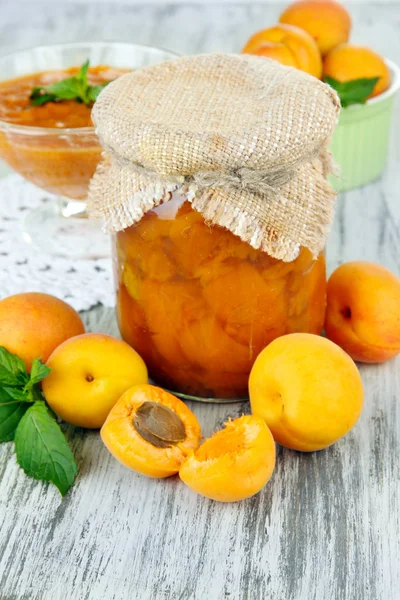 Marmellata di albicocche in vaso di vetro e albicocche fresche, su fondo di legno — Foto Stock