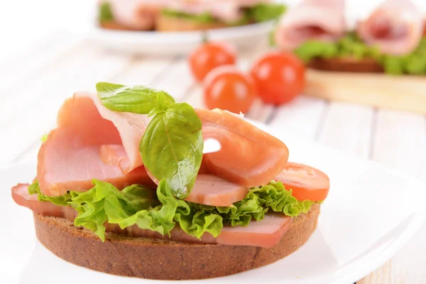 Вкусный сэндвич с салатом и ветчиной на тарелке на столе крупным планом — стоковое фото