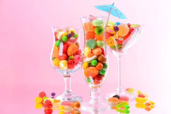 Forskellige farverige frugt slik i briller på lyserød baggrund - Stock-foto
