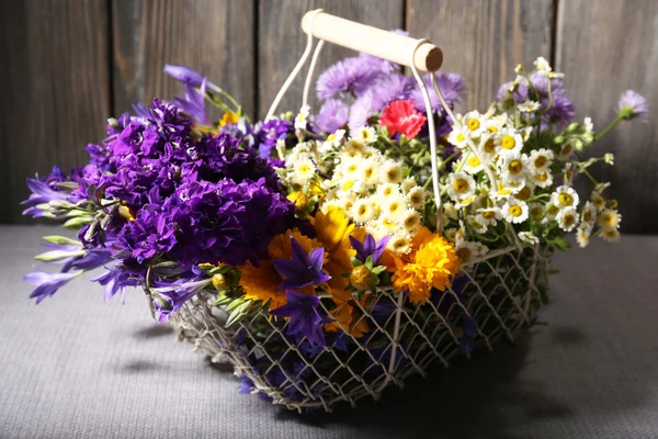 Prachtige wilde bloemen in mand op houten achtergrond — Stockfoto