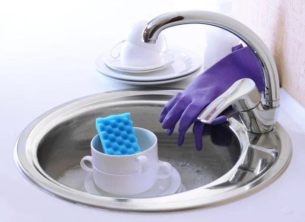 Stack of dishes soaking in kitchen sink — Stock Photo, Image