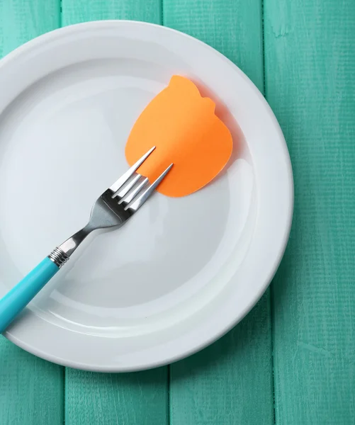 Empty note paper attached to fork, on plate, on color wooden background — Stock Photo, Image