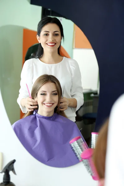 Mujer joven peluquera hacer peinado chica en salón de belleza — Foto de Stock