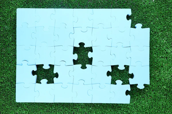 Puzzle pieces on green grass — Stock Photo, Image