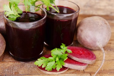 Tahta arka planda taze pancar suyu ve sebzeler.