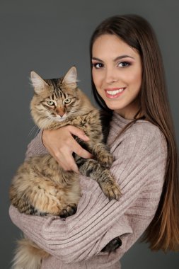 Güzel ve genç birbayan holding kedi gri arka plan üzerinde