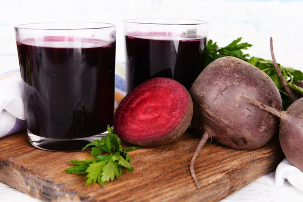 Glasses of fresh beet juice and vegetables on cutting board on wooden background — Stock Photo, Image