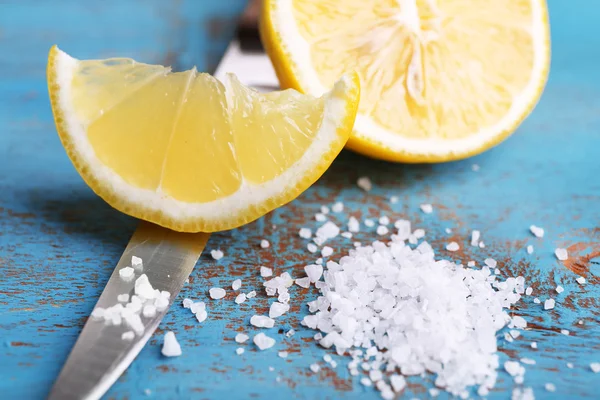 Still life with fresh lemon, knife and salt on old wooden table — Stock Photo, Image