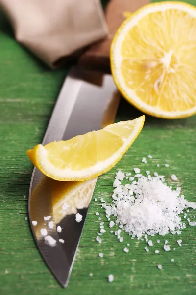 Still life with fresh lemon, knife and salt on old wooden table — Stock Photo, Image