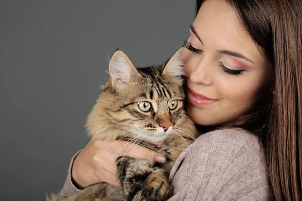 Mulher bonita segurando gato no fundo cinza — Fotografia de Stock