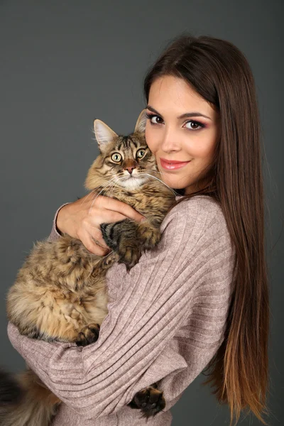 Hermosa mujer joven sosteniendo gato sobre fondo gris — Foto de Stock
