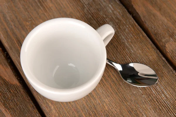 Empty cup with tea spoon on wooden background — Stock Photo, Image