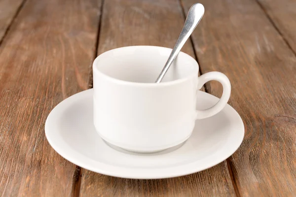 Empty cup with tea spoon on wooden background — Stock Photo, Image