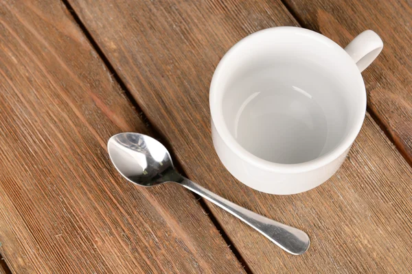 Leere Tasse mit Teelöffel auf Holzgrund — Stockfoto