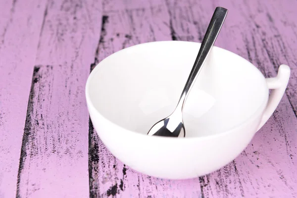 Empty cup with tea spoon on wooden background — Stock Photo, Image